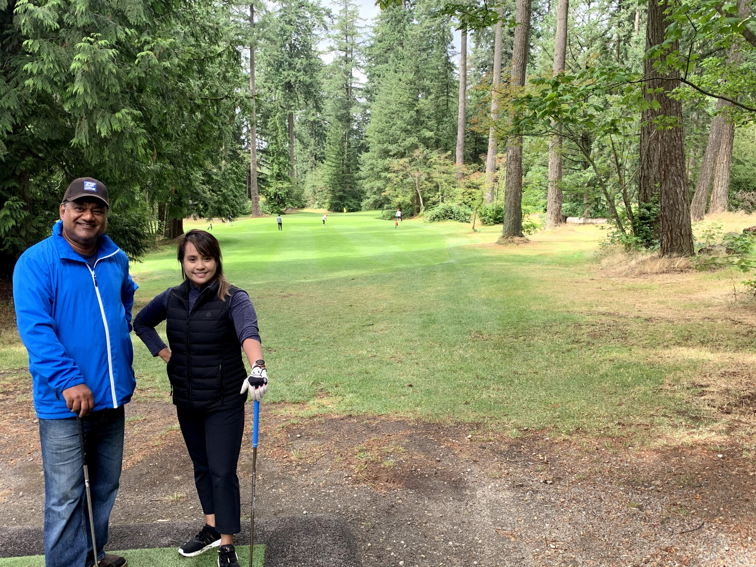 Man and woman smiling with golf clubs on fairway at Central Park Pitch and Putt Vancouver social golf event