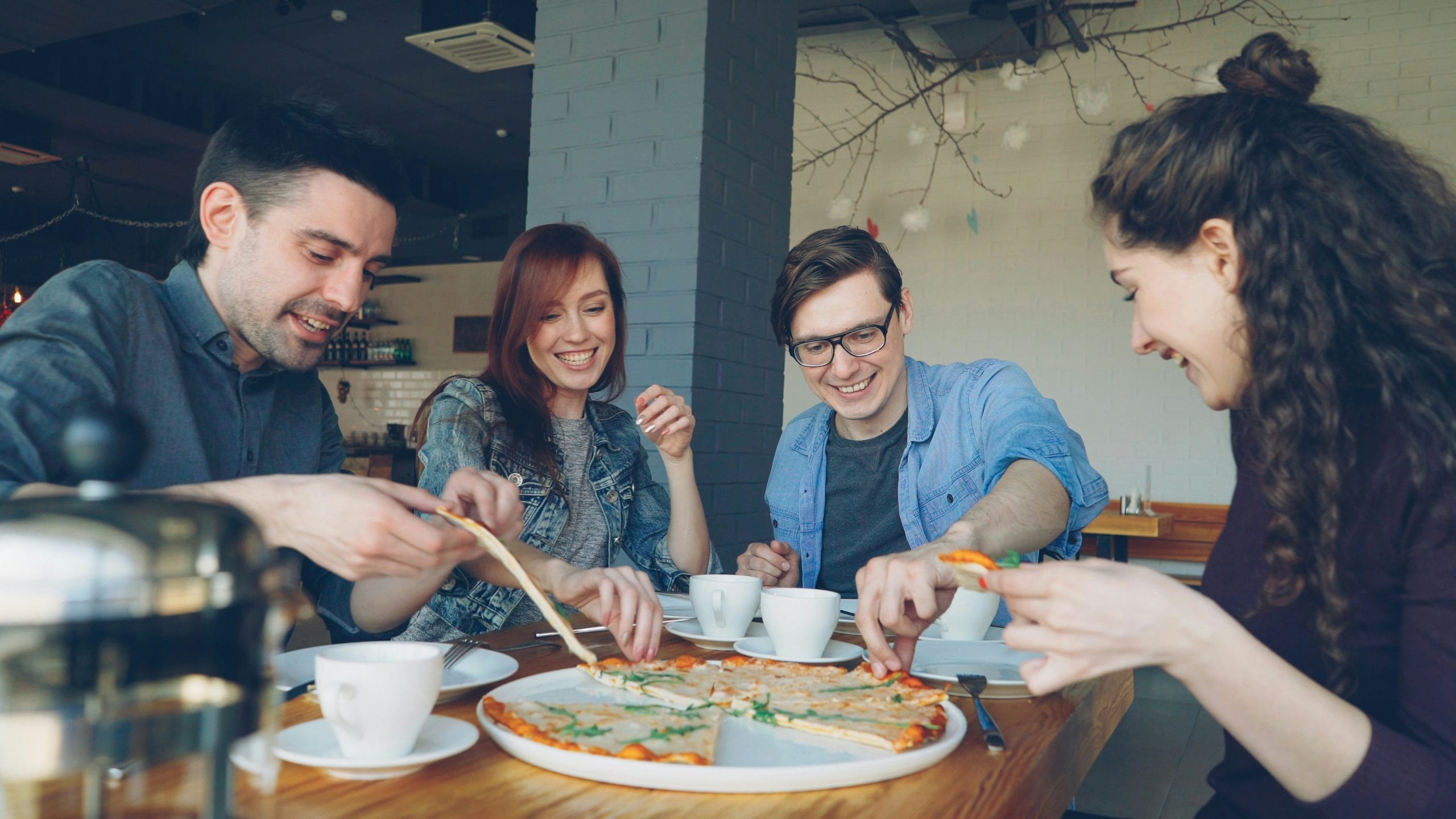 Friends laughing together while sharing pizza, an easy way to meet people Vancouver locals enjoy